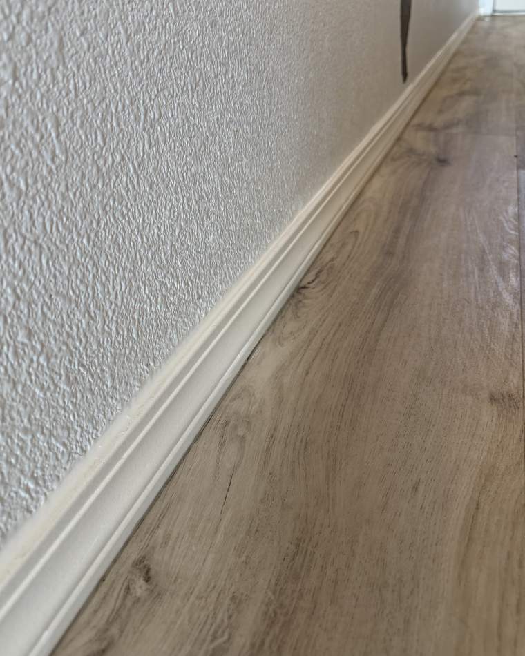The same baseboard after cleaning, with the trim and the floor beside it clear