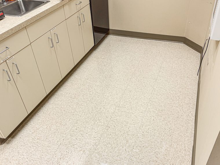 The same break room floor after stripping and waxing, with an even gloss