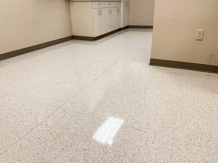 The same office floor after stripping and waxing, reflecting the ceiling lights