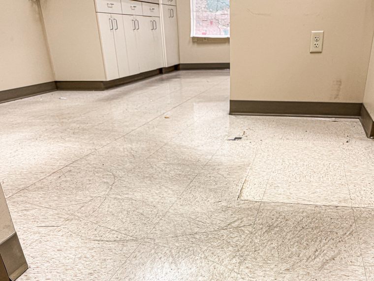 Office tile floor before stripping, scuffed and scratched across the tile