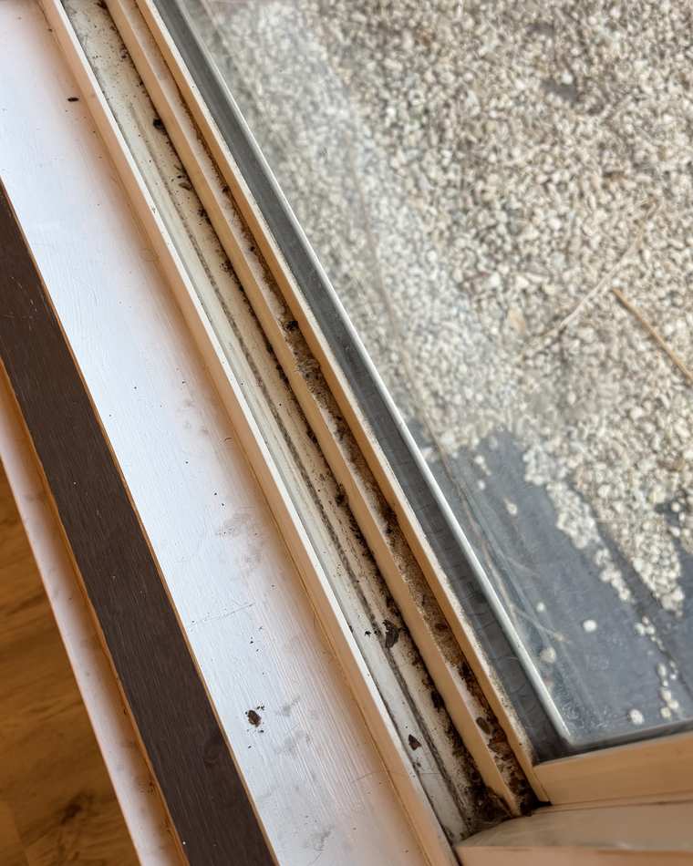 Sliding glass door track before cleaning, packed with dirt and debris along the channel
